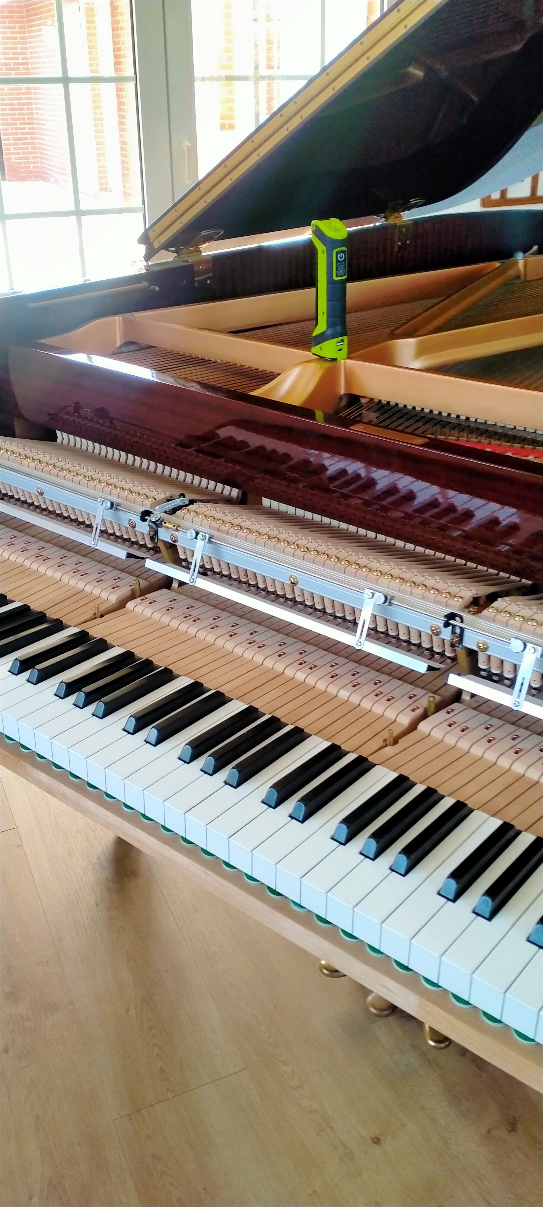 Piano de cola con sistema silenciador mostrando teclado y mecanismo