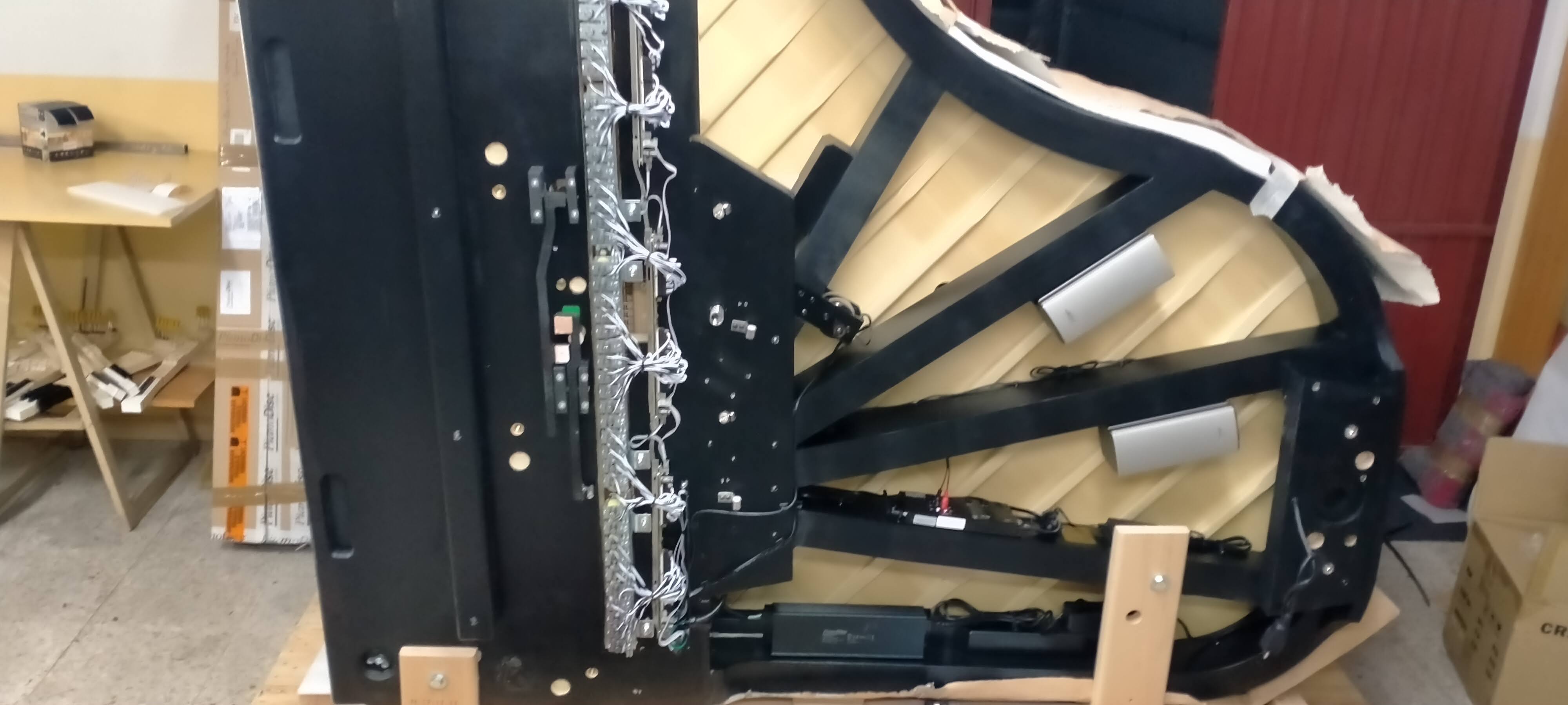 Piano de cola negro volteado mostrando cableado del sistema