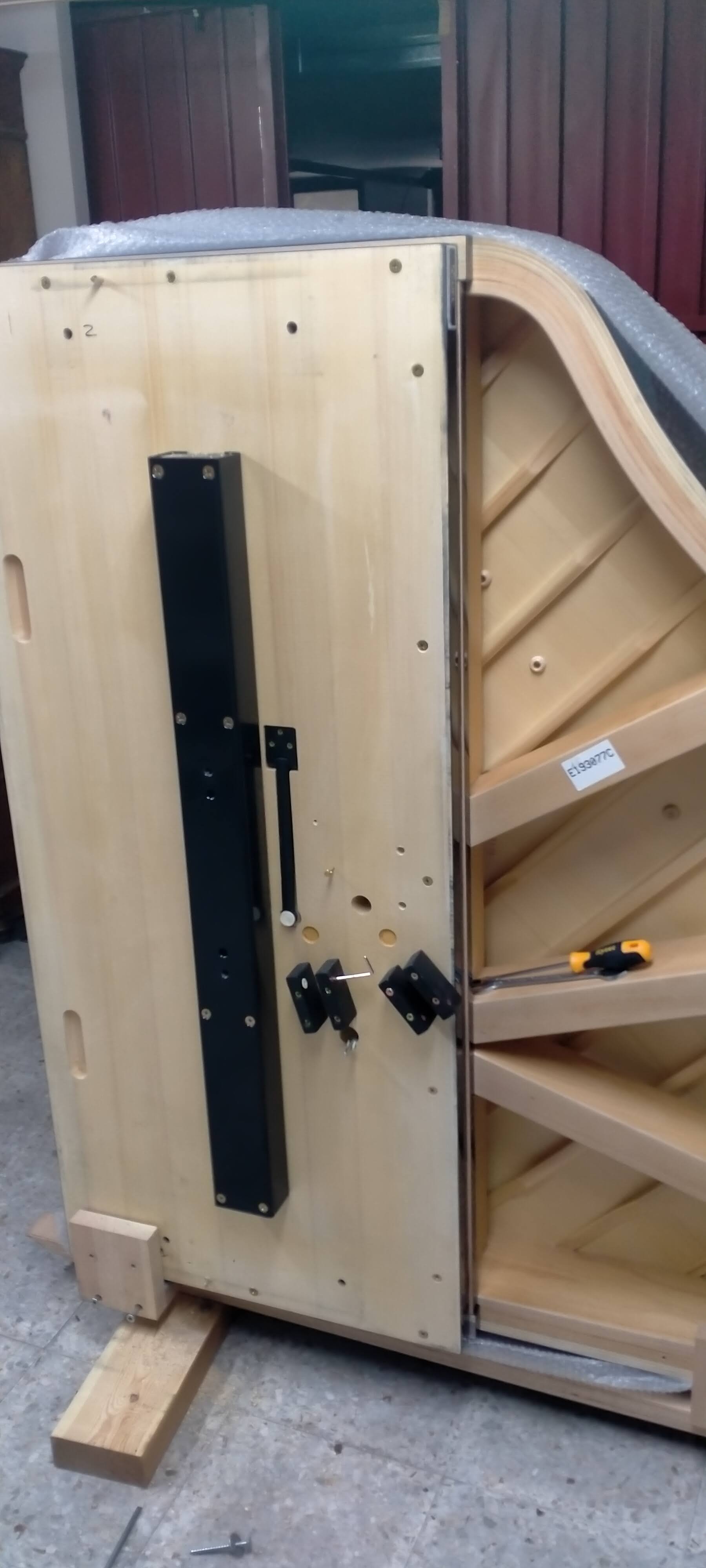 Piano de cola en proceso de construcción con cableado visible